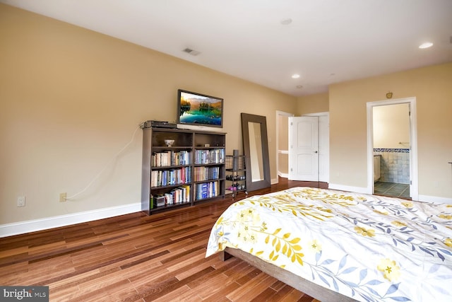 bedroom with connected bathroom and hardwood / wood-style floors