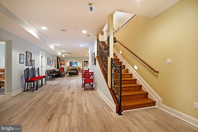 stairway with wood-type flooring and ornamental molding