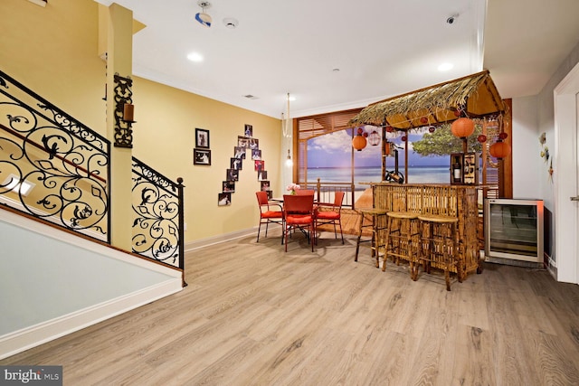 dining room with wine cooler, bar, and light wood-type flooring