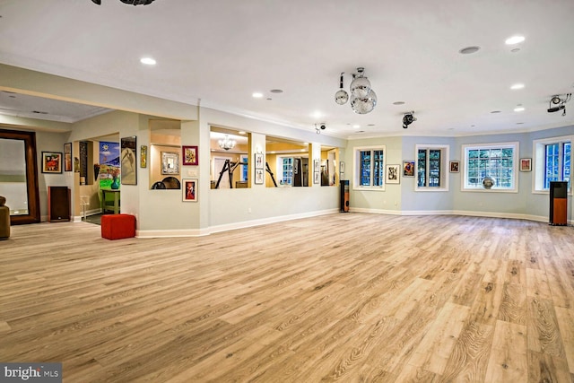 unfurnished living room featuring ornamental molding and light wood-type flooring