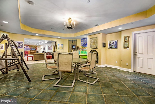 dining room featuring dark tile patterned flooring, a raised ceiling, and a chandelier