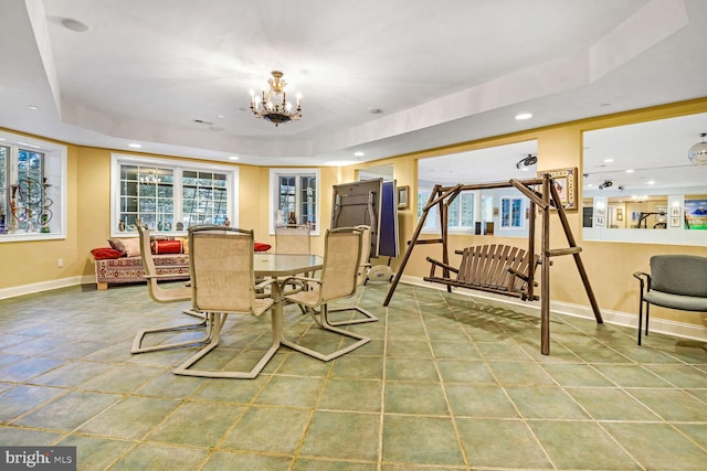 dining space with a notable chandelier, a tray ceiling, and a wealth of natural light