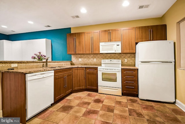 kitchen featuring light stone counters, sink, white appliances, and decorative backsplash