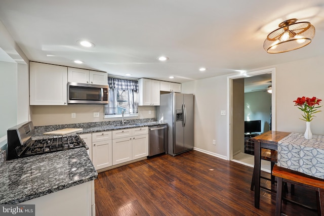 kitchen with white cabinetry, sink, dark stone countertops, stainless steel appliances, and dark wood-type flooring