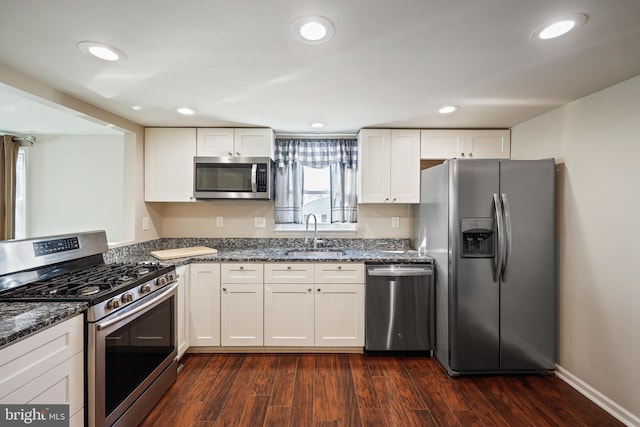 kitchen with dark wood-type flooring, sink, white cabinetry, dark stone countertops, and appliances with stainless steel finishes