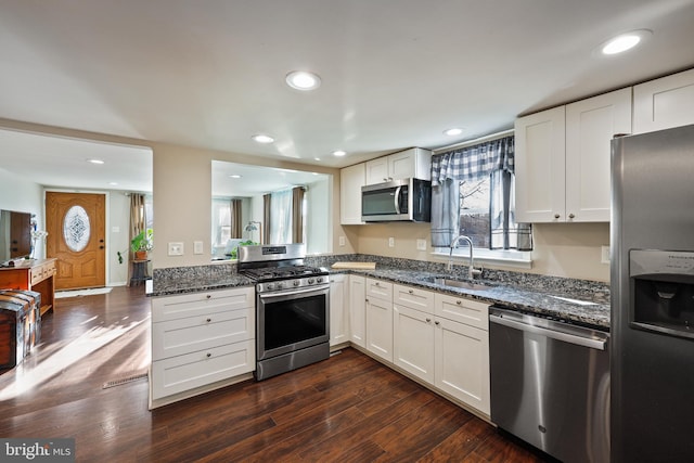 kitchen with dark stone countertops, sink, stainless steel appliances, and white cabinets