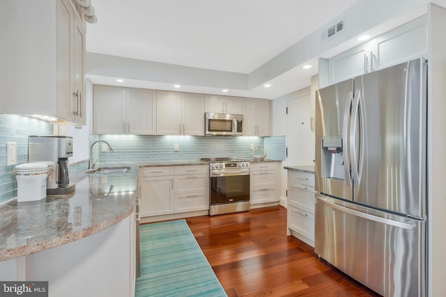 kitchen with backsplash, sink, white cabinetry, appliances with stainless steel finishes, and dark hardwood / wood-style flooring