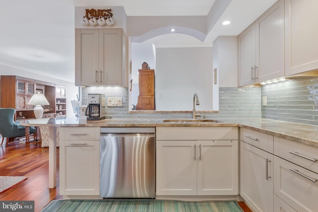 kitchen with decorative backsplash, sink, dishwasher, and kitchen peninsula