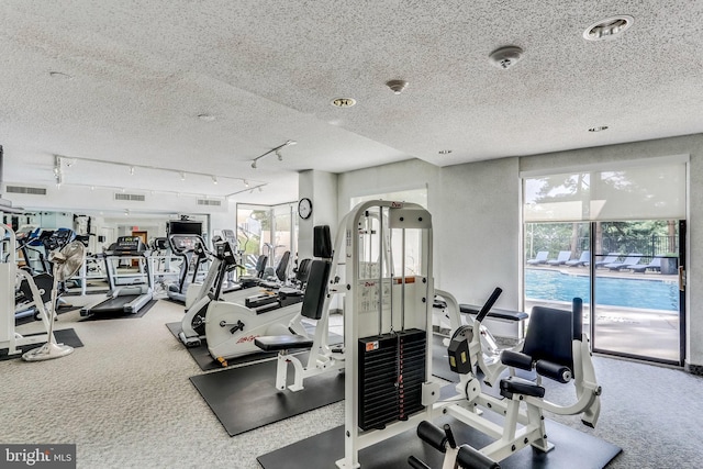 workout area featuring a textured ceiling, track lighting, and carpet flooring