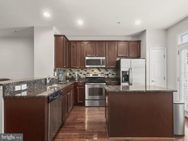 kitchen featuring dark wood-type flooring, sink, dark stone countertops, appliances with stainless steel finishes, and decorative backsplash