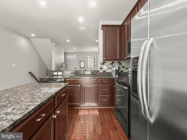 kitchen featuring sink, stainless steel fridge, dark stone countertops, dark hardwood / wood-style flooring, and black / electric stove