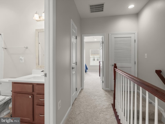 corridor with sink and light colored carpet