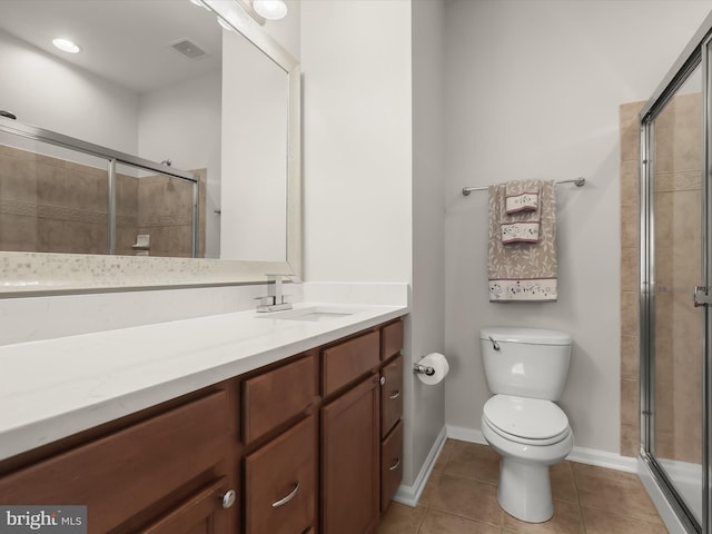 bathroom featuring tile patterned flooring, vanity, a shower with shower door, and toilet