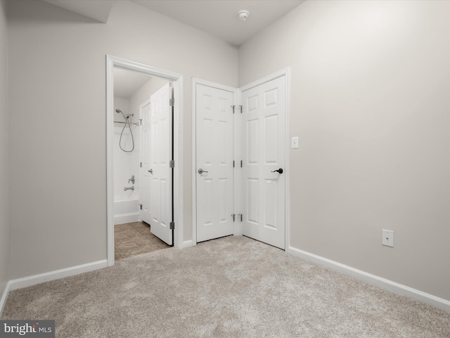 unfurnished bedroom featuring light colored carpet and ensuite bath