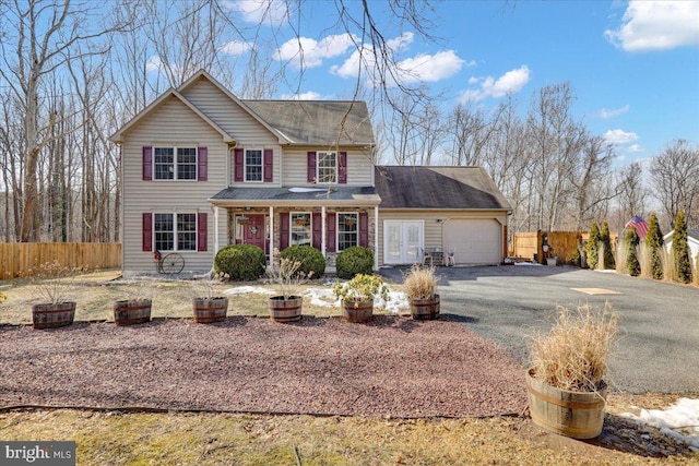 view of front of home with an attached garage, a porch, fence, and aphalt driveway