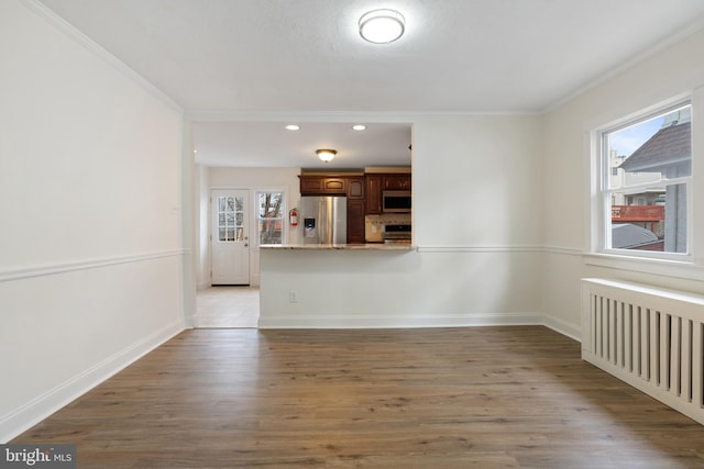 unfurnished living room with dark wood-type flooring, radiator heating unit, and ornamental molding