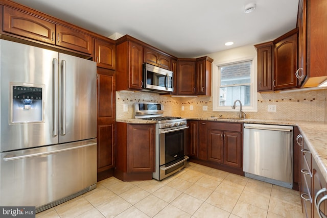 kitchen with light stone countertops, sink, appliances with stainless steel finishes, and tasteful backsplash