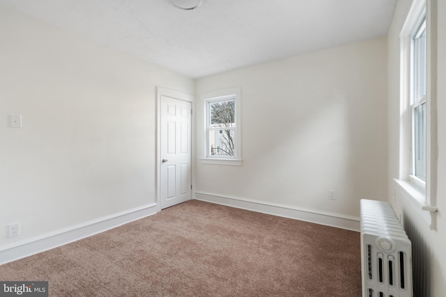 carpeted spare room with plenty of natural light and radiator heating unit