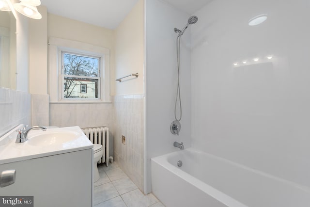 full bathroom with radiator, tile patterned floors, washtub / shower combination, vanity, and tile walls