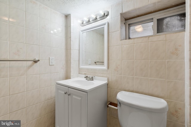 bathroom featuring toilet, vanity, tile walls, and a textured ceiling