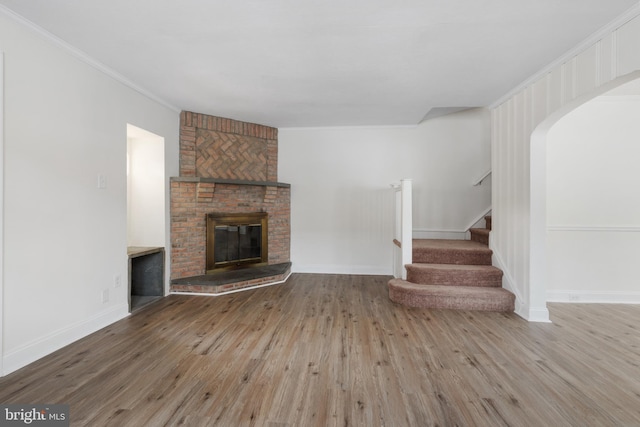 unfurnished living room with a fireplace, ornamental molding, and hardwood / wood-style floors