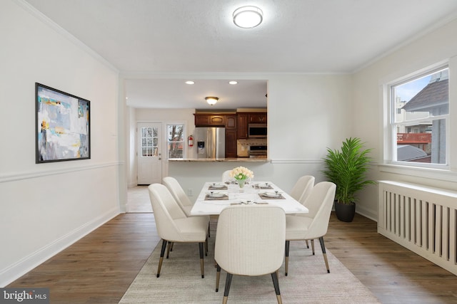 dining space featuring crown molding, light hardwood / wood-style flooring, and radiator heating unit