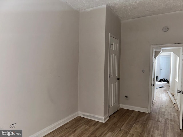 corridor with a textured ceiling and hardwood / wood-style flooring