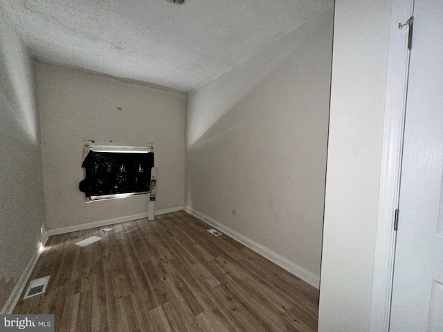 unfurnished room with a textured ceiling and hardwood / wood-style flooring