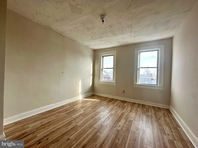 spare room with a textured ceiling and light hardwood / wood-style flooring