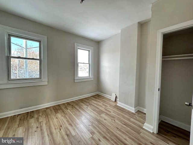 unfurnished bedroom featuring a closet, light hardwood / wood-style flooring, and multiple windows