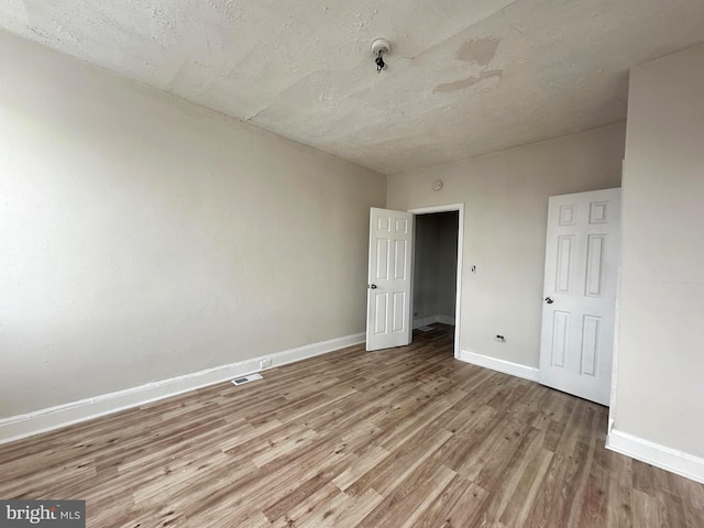 spare room with light hardwood / wood-style floors and a textured ceiling