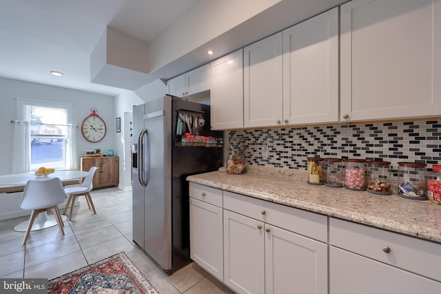 kitchen with stainless steel fridge with ice dispenser, white cabinetry, decorative backsplash, and light stone countertops