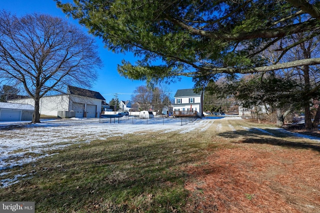 yard covered in snow featuring a garage and an outbuilding