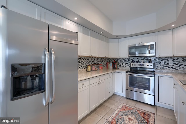 kitchen with light stone counters, white cabinets, appliances with stainless steel finishes, and light tile patterned floors