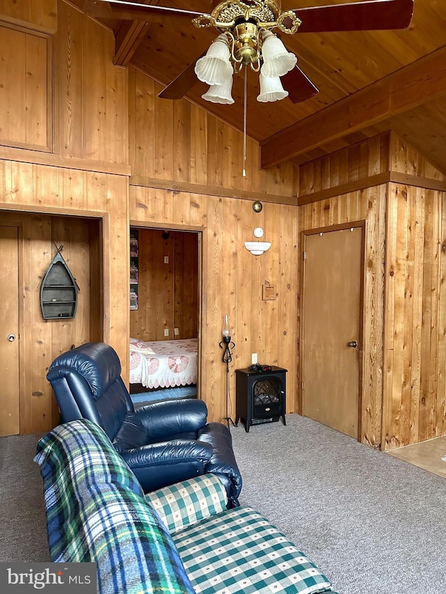 living room featuring carpet floors, wooden walls, a wood stove, and wooden ceiling