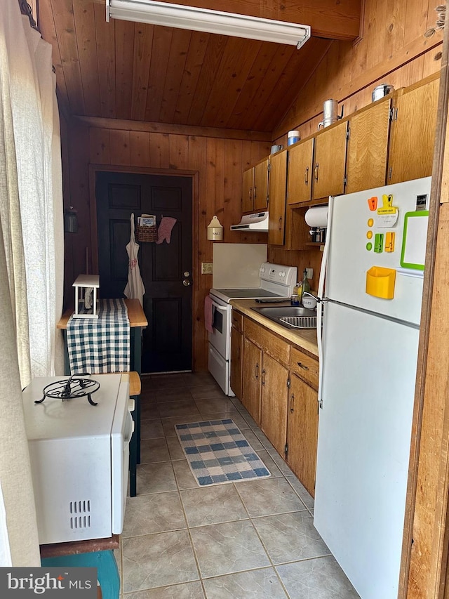 kitchen with white appliances, sink, wood walls, lofted ceiling with beams, and light tile patterned floors