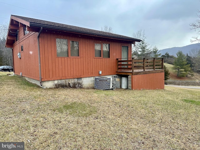 view of side of home with a mountain view, a yard, and central air condition unit