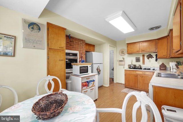 1113 Cameron Rd, Alexandria, VA 22308 - kitchen with a sink, white appliances, light wood-type flooring, light countertops, and brown cabinets