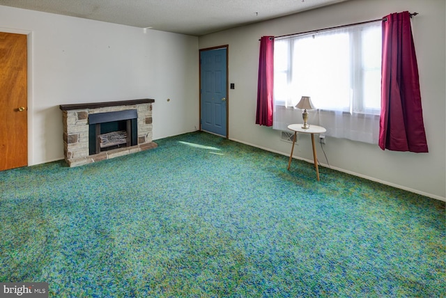 unfurnished living room featuring a textured ceiling, carpet, and a stone fireplace