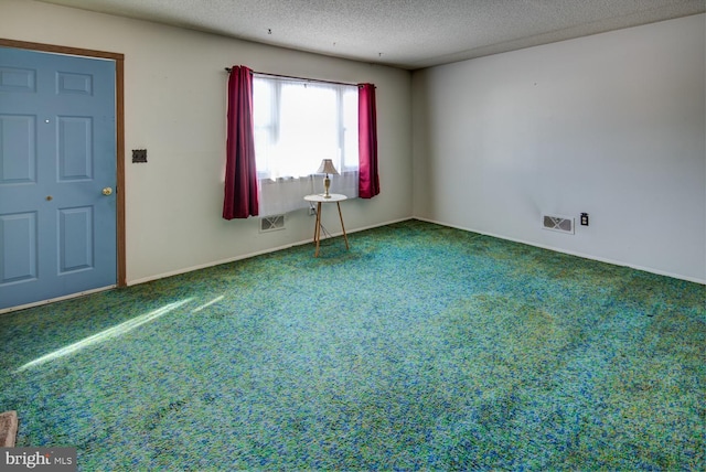 carpeted empty room featuring a textured ceiling