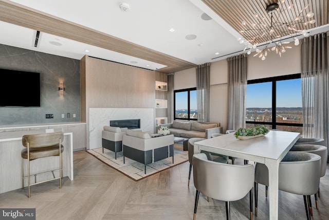 dining area featuring light parquet flooring, a premium fireplace, and a chandelier