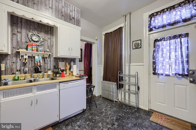 kitchen featuring sink, white dishwasher, white cabinets, and radiator heating unit