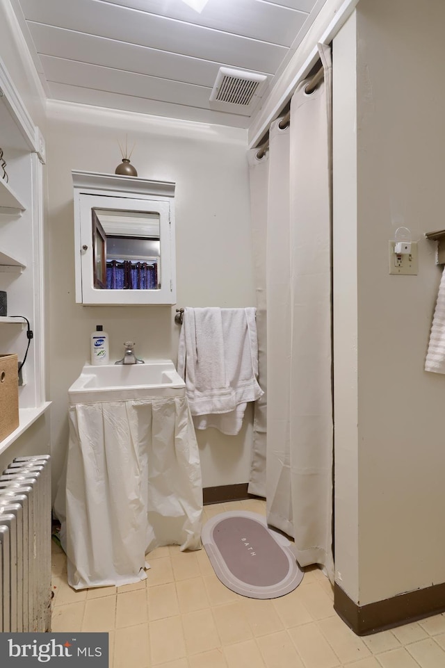 bathroom featuring sink, radiator heating unit, and ornamental molding