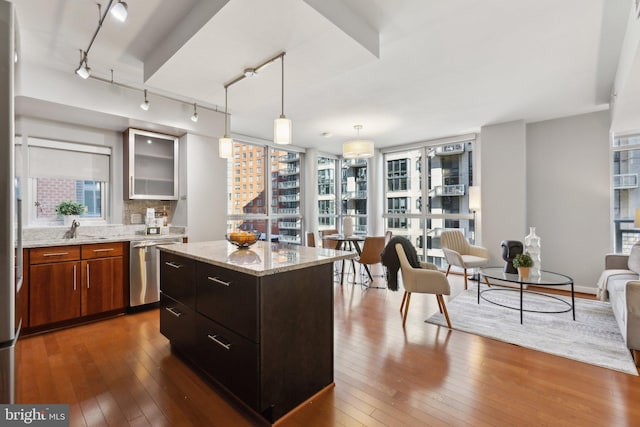 kitchen featuring pendant lighting, a kitchen island, dark wood-type flooring, decorative backsplash, and stainless steel dishwasher