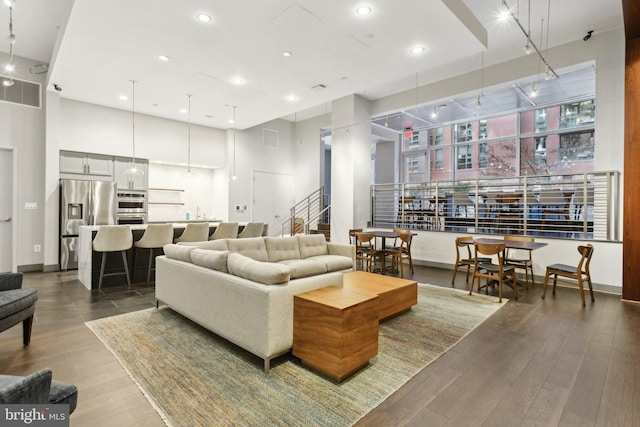 living room featuring wood-type flooring, a high ceiling, and rail lighting