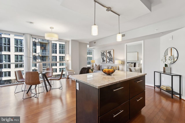 kitchen with wood-type flooring, hanging light fixtures, a center island, and dark brown cabinets