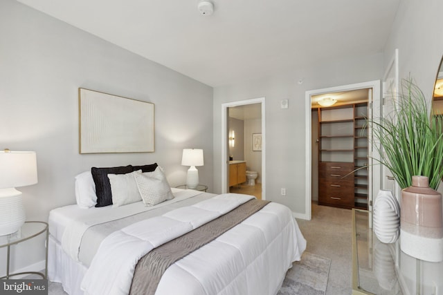 bedroom featuring ensuite bath, a closet, a spacious closet, and light carpet