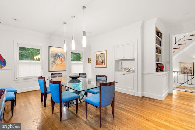 dining room with ornamental molding, light hardwood / wood-style flooring, and built in shelves