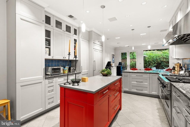 kitchen with a kitchen island, white cabinetry, tasteful backsplash, ventilation hood, and high end stove