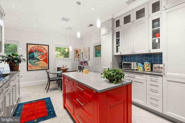 kitchen featuring white cabinets, a center island, tasteful backsplash, ornamental molding, and light tile patterned flooring